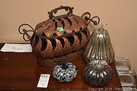 Overview of all items including metal container and three glass pumpkin ornaments on wooden surface