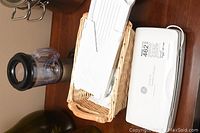 Magic Bullet food processor cup, mandolin parts in basket, and GE carving set case on table.