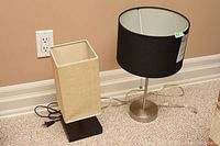 Both lamps together showing difference in lampshade shape and size, on carpet floor near power outlet