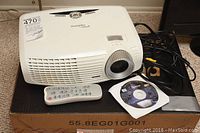 Top-front view showing projector, remote and user manual CD on original box