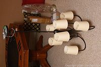 Visual Comfort chandelier with 8 cream-colored cylindrical fabric shades on a black metal frame, lying on floor near wood table.