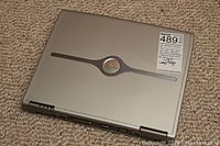 Closed view of the silver Dell Inspiron 600m laptop showing the Dell logo on the lid and a sticker indicating model information.