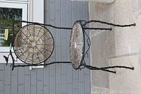 Photo of decorative garden chair showing black metal frame and round woven seat on patio