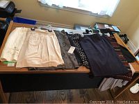 Multiple ladies skirts laid out on a table showing different styles and colors.