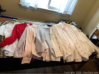 Seven assorted women's tops and shirts laid out on bed