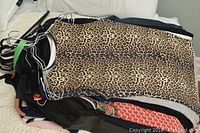 Stack of assorted women’s tops, dresses and sweaters on hangers