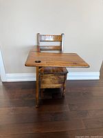 Front view of the antique wooden child’s desk showing chair, writing surface, inkwell hole