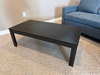 Full view of black wood coffee table beside sofa
