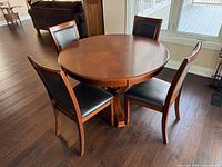 Round wooden dining table with four matching chairs