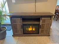 Front view showing TV stand, fireplace insert lit, sliding doors open