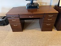 Front view of wood executive desk showing seven drawers and kneehole