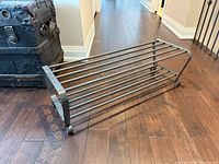 Full view of metal 2-tier shoe rack on wooden floor