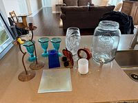 All items arranged on countertop including dispenser, vase, goblets, plate, candle holders and décor pieces