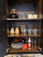 Cabinet view showing teapot, mugs, wine glasses, two glass tumblers, bowls and plates