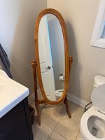 Front view of oval wood cheval floor mirror