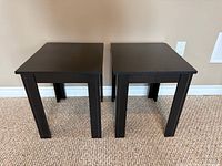 Front view of both black wood side tables showing tops and legs