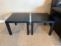 Front view of both black-brown IKEA LACK side tables side by side on carpet