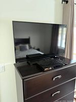 Front view of Toshiba 40-inch LED TV on dresser with stand and accessories