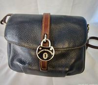 Front view showing pebbled leather body, flap, medallion closure