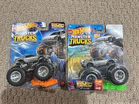Front view of both sealed Hot Wheels Monster Trucks Back to the Future DeLorean vehicles on cards