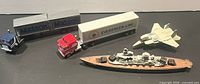 Overview of all diecast pieces: two semi trucks with trailers, jet, battleship