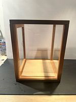 Overall view of wood and glass display case showing front door, glass sides, mirrored back, open top