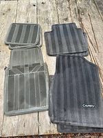 stacked set of four rubber and four carpet Toyota Camry floor mats displayed on wooden surface