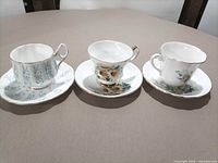 three teacup and saucer sets displayed side by side