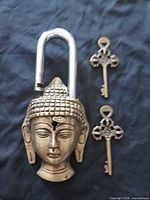 Full view of brass Buddha head padlock with two ornate keys