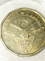 Reverse of coin showing 1917-2017 dates, crossed sticks, maple leaf