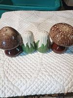 Front view of two mushroom and two corn shakers displayed side by side