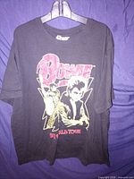 Full front view of black Bowie 1972 World Tour t-shirt on hanger