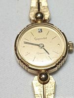 Close view of watch dial showing brand, crystal marker, hands and bezel