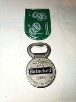 Front view of metal Heineken bottle opener and green sleeve