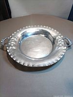 Full view of round silver-plated tray showing handles and rim