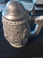 Full stein showing relief artwork and pewter globe lid