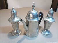 Teapot centred between salt and pepper shakers showing overall set