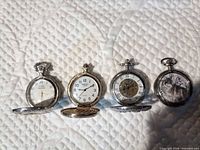 Front view of all four pocket watches with covers open