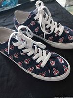 Side view of both sneakers showing Cleveland Indians pattern and white laces