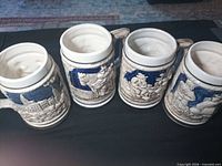 Four steins top view showing interiors and relief exteriors