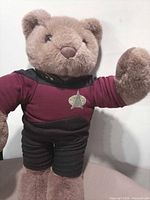 Full view of plush teddy bear standing, right arm raised