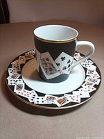 Cup on saucer showing playing card design and gold trim