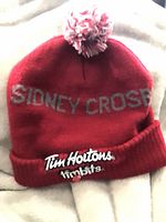 Full view of red pom beanie showing SIDNEY CROSBY text and pom