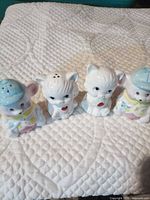 Front view of all four porcelain animal shakers on quilted surface