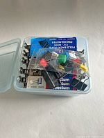 Closed plastic container showing assorted binder clips and packaging