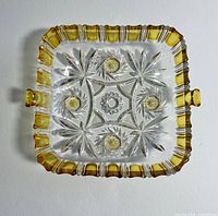 Top view of square pressed glass dish showing starburst design and amber rim