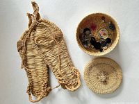 Top view of open trinket basket with lid and contents alongside straw sandals