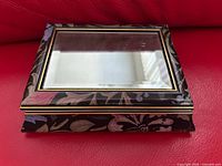 Closed jewelry box showing mirrored top and floral sides