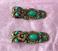 front view of both brass shoe clips showing green stones and floral filigree
