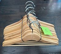Stack of ten wooden hangers showing hooks and wood finish